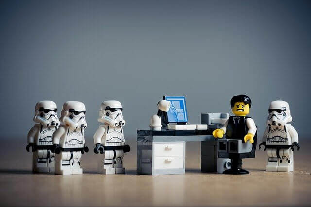 Quatre stormtroopers en légo encerclent le bureau d'un salarié crispé.
