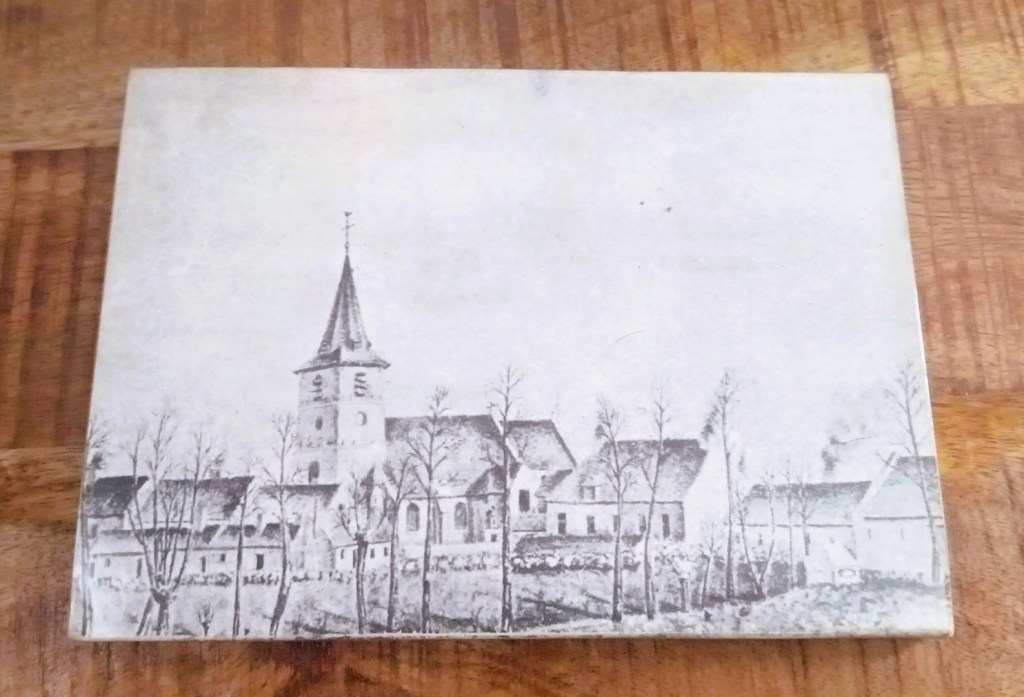 Dessin monochrome représentant une vue du village de Ghlin dominée par le clocher d'une église, avec des maisons anciennes alignées derrière une rangée d'arbres.